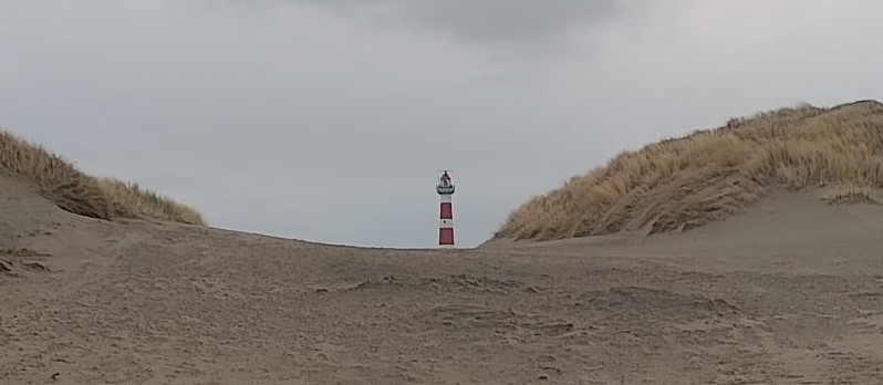 Vuurtoren Ameland vanaf een strandopgang, links en rechts duinen, een grauwe lucht